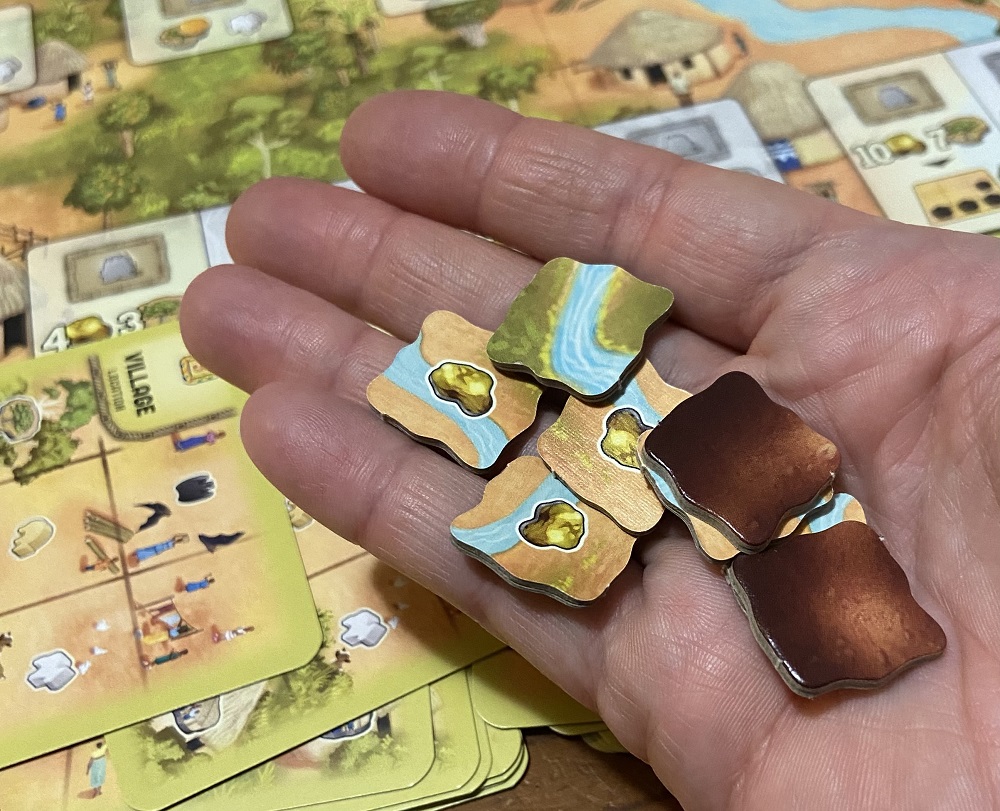 image of a hand holding pollution tokens from the game Atiwa