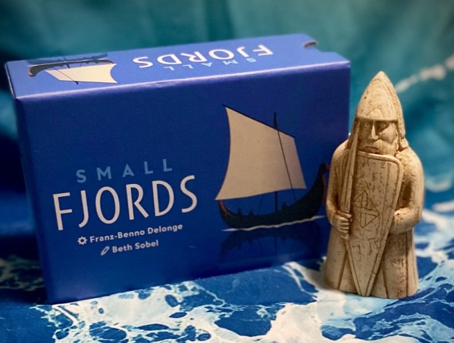 photo of box for Small Fjords, with blue background and a stone carving viking chess piece