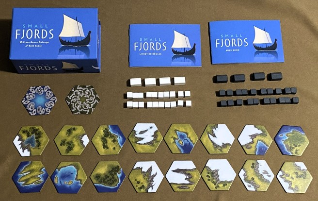 photo of all components included in the tabletop game Small Fjords, including tiles, box, instructions, and wooden placements pieces