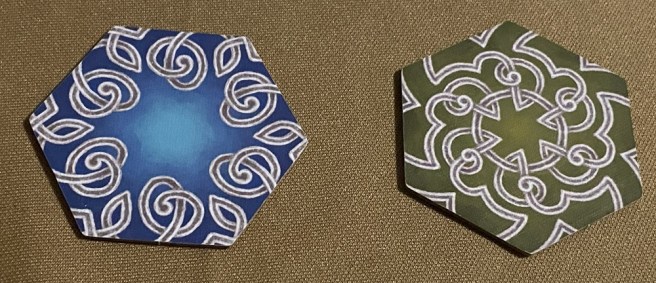 photo of the back of the tiles from the tabletop game Small Fjords, featuring Norse knotwork on a blue background and on a green background