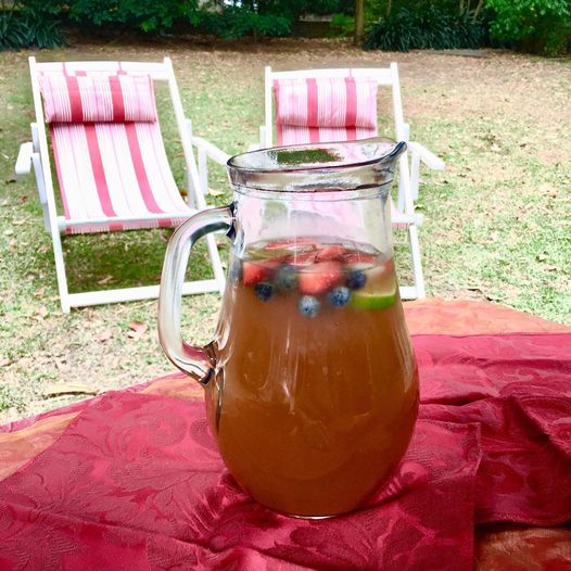 image of fruit punch in a glass jug with two deck chairs in the background on a sunny summer day