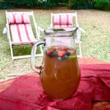 image of fruit punch in a glass jug with two deck chairs in the background on a sunny summer day