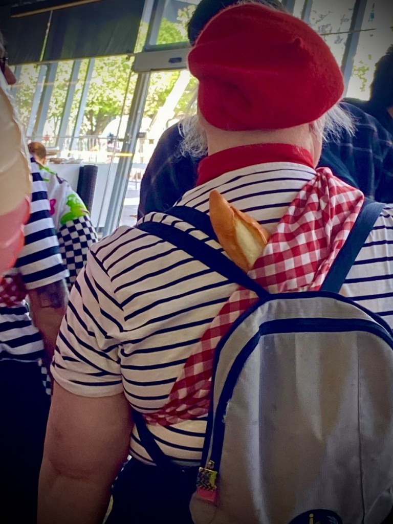 Image of the back of a cosplay artist carrying a baguette on their back like the characters from Clair Obscura Expedition 33